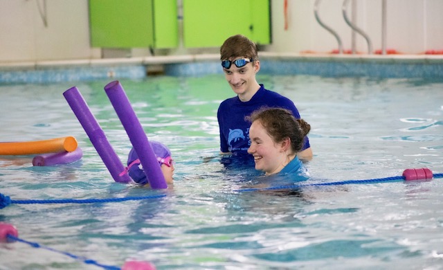 Swimmers at the poolside wall